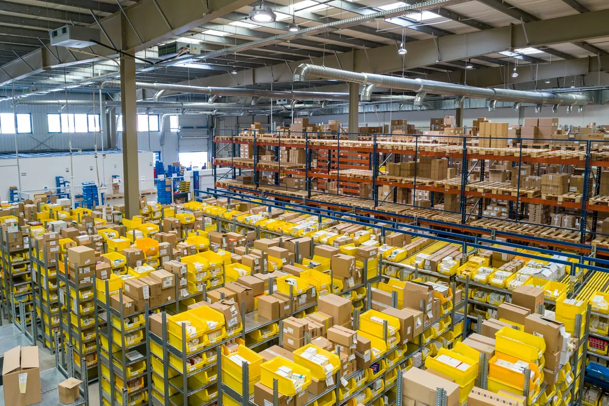 Almacén de distribución retail con anaqueles altos organizados por flujo logístico.