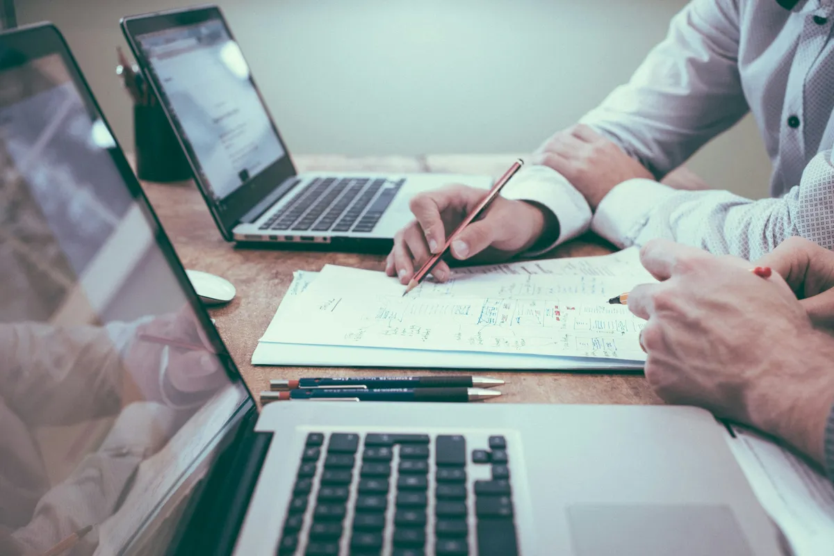 Análisis técnico sobre documentos y laptops en escritorio profesional.